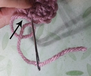 Weaving in the ending tail. Arrow indicates the slip stitch.